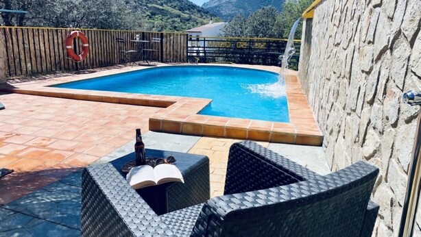 Une piscine avec une vue sur les montagnes, une clôture en bois et du mobilier d’extérieur.
