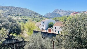 Un quartier résidentiel situé sur une colline, avec des maisons, un mur de pierre et un ciel bleu dégagé.