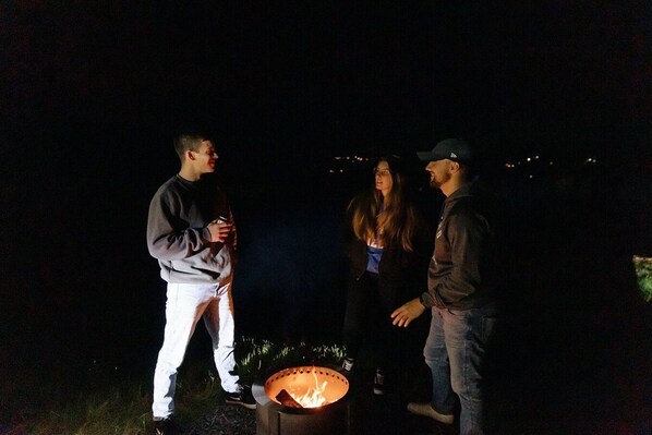 Un grupo de personas reunidas alrededor de una fogata por la noche.