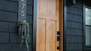 Una casa de exterior oscuro, con una puerta principal de madera y el número '275' en la pared.