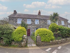 A stone house with a red door, a stone wall, and a metal gate. - Glanrafon (Llwyngwril)
