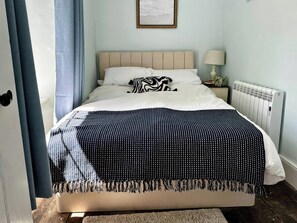 Un lit avec une tête de lit, une table de chevet avec une lampe et un radiateur.