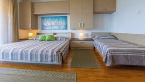A hotel room with two beds, a painting, wooden cabinets, and a nightstand with lamps. - Very nice studio apartment with sea view, balcony & parking space (Crikvenica)
