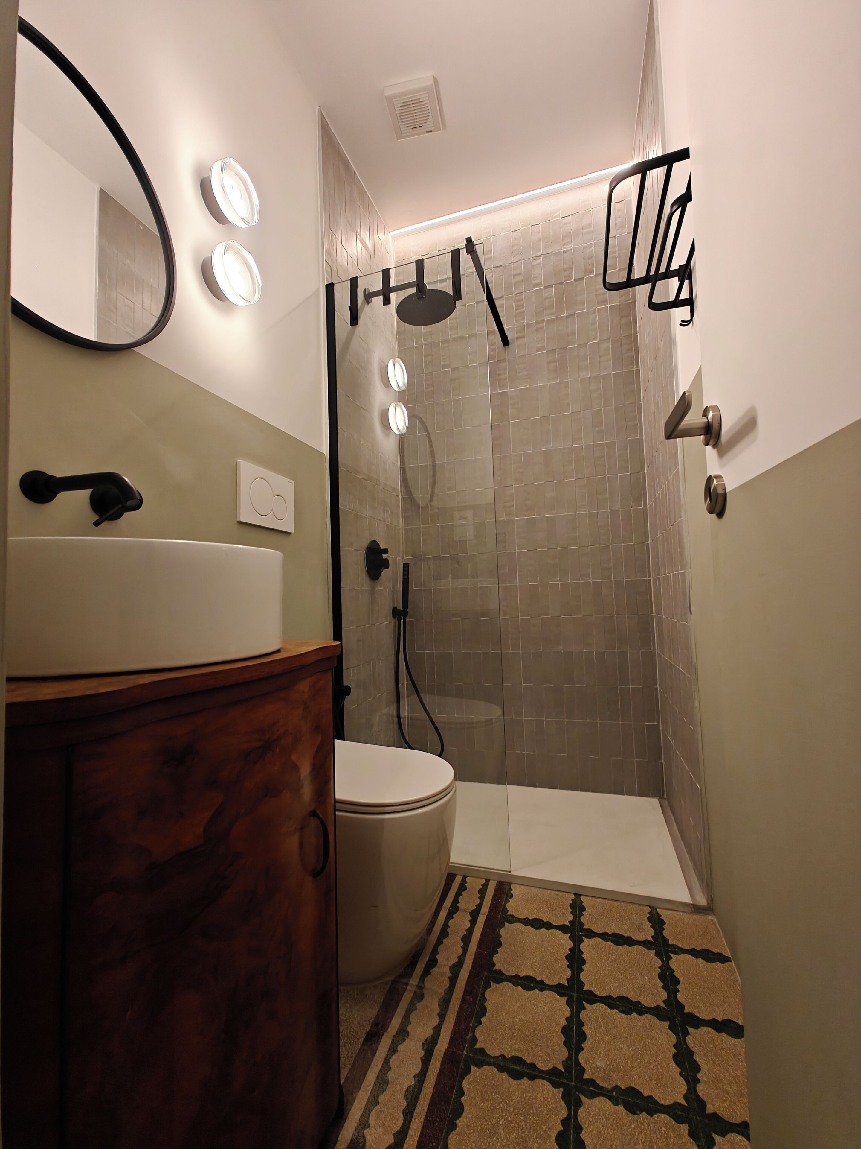 A bathroom with a toilet, a sink, a mirror, and a shower with a glass door.