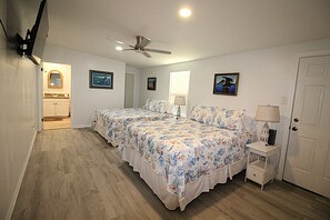 Ein Schlafzimmer mit zwei Betten, einem Deckenventilator und einer Tür.