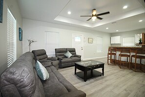 A living room with a sectional sofa, a recliner, a glass coffee table, and a ceiling fan. - Newly remodeled home where the wildlife roam! (Port Mansfield)