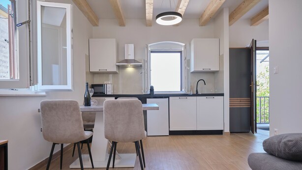 Eine moderne Küche mit weißen Schränken, einem Essbereich mit zwei Stühlen und einem Holzboden.