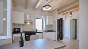Eine moderne Küche mit weißen Schränken, einem eingebauten Ofen und einem Essbereich mit Tisch und Stühlen.