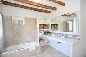 Ein modernes Badezimmer mit Glasdusche, weißem Waschtisch und Holzbalken an der Decke.