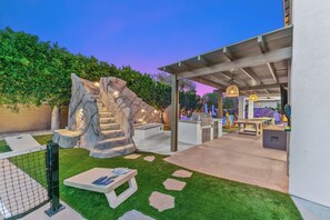 Een moderne patio met een rotsdecoratie, een barbecuehoek en een overdekte zithoek.