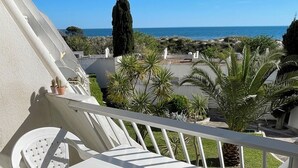 Una terraza con mesa y sillas, baranda y vista al mar y al paisaje.