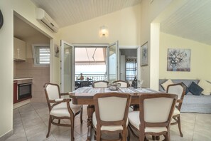 A dining area with a table and chairs, a kitchen with an oven, and a balcony with a view. - Flor di Mar - 3BR Apt by the Sea, Okrug Gornji (Okrug Gornji)