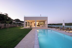 A modern house with a swimming pool, outdoor seating, and a view of the water. - Villa Neratzia - Luxury Escape (Platanias)