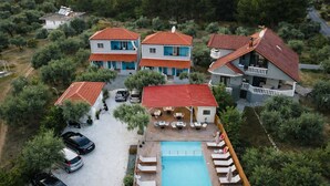 Una proprietà residenziale con piscina, diverse case e auto parcheggiate.