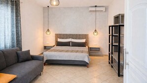 Una camera da letto con un letto, un divano, un armadio e lampade a sospensione.