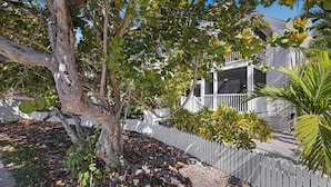 A tree-lined residential area with a white picket fence, a house with a screened porch, and a paved walkway. - A Cayo Hueso Retreat at the Key West Golf Club (Key West)