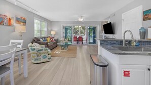 A modern kitchen with a built-in stove, a dining area with a white table and chairs, and a living room with a sofa and a coffee table. - A Cayo Hueso Retreat at the Key West Golf Club (Key West)