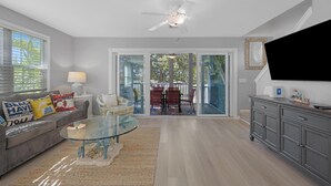 A living room with a glass coffee table, grey sofa, and a ceiling fan. - A Cayo Hueso Retreat at the Key West Golf Club (Key West)