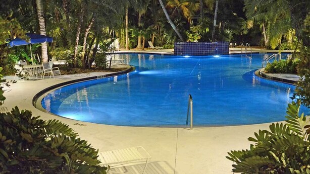 A circular pool with a blue tile border, surrounded by palm trees and lounge chairs. - A Cayo Hueso Retreat at the Key West Golf Club (Key West)
