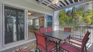 A covered patio with a table and chairs, large windows, and a ceiling fan. - A Cayo Hueso Retreat at the Key West Golf Club (Key West)