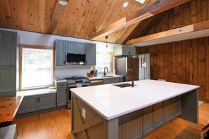 A modern kitchen with wooden beams, a large island, and built-in appliances.