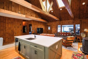 A wooden interior with a kitchen island, a sofa, and a fireplace.