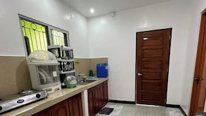 A kitchen with a stove, sink, cabinets, and a door. - Yena's Inn (Cauayan)