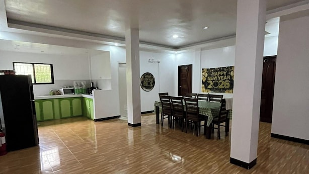 A spacious living area with a dining table, kitchen in the background, and a 'Happy New Year 2026' decoration. - Yena's Inn (Cauayan)