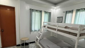 A room with a bunk bed, a small round table, a door, and a window with curtains. - Yena's Inn (Cauayan)