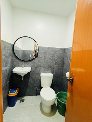 A small bathroom with a toilet, sink, and mirror. - Yena's Inn (Cauayan)