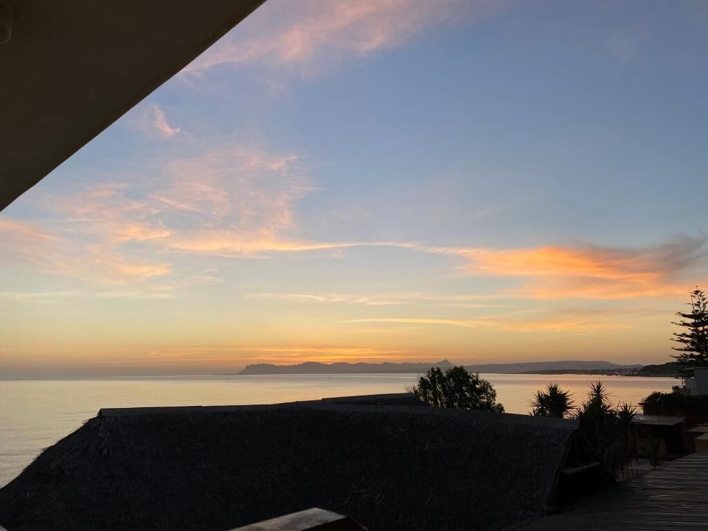 A coastal view with a clear sky, a body of water, and a stone wall.