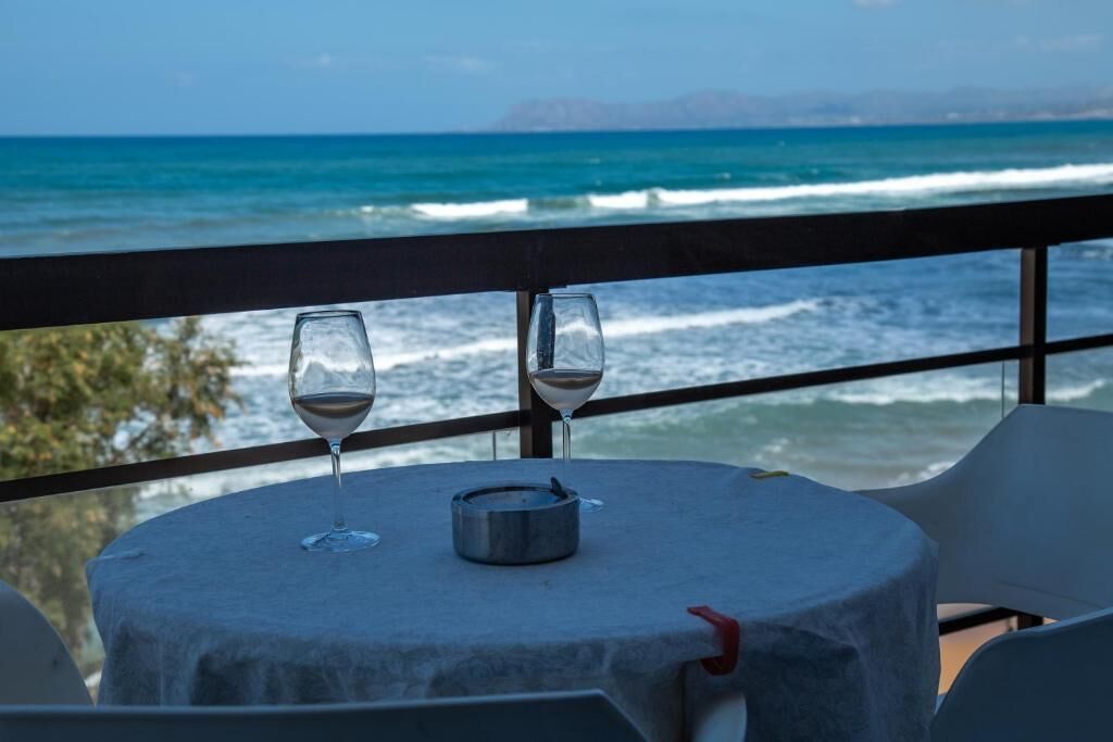 A table with two glasses and a metal container, overlooking the ocean.