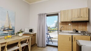 Una cocina con armarios de madera, un microondas, un lavamanos y vistas al exterior.
