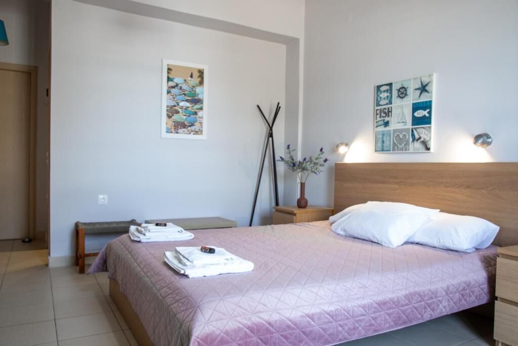 A neatly made bed with a headboard, a bedside table with a lamp, and a wall with two framed pictures.