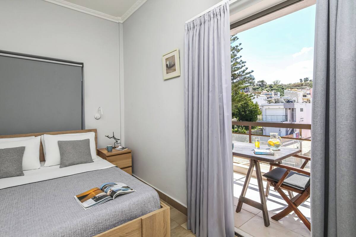 Un dormitorio con cama, mesita de noche y vistas al exterior.