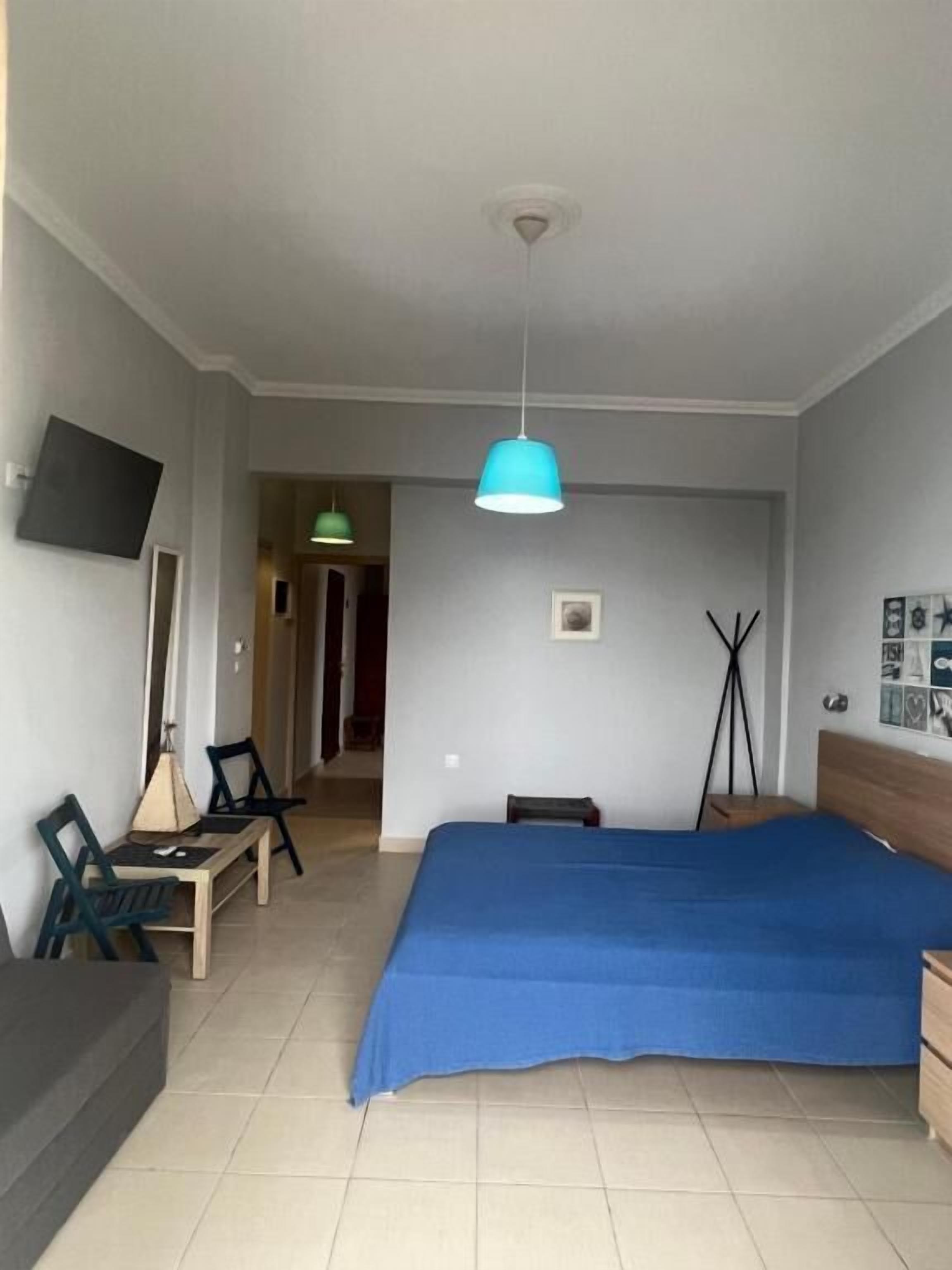 A bedroom with a bed, a desk, a chair, a TV, and a ceiling light.