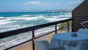 Un restaurante frente al mar, con vista al océano, mesas y sillas, y un edificio de madera.