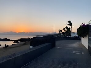 Een kustpad met uitzicht op de zee en verre bergen.