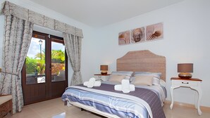 Ein Schlafzimmer mit Bett, Vorhängen, Nachttisch, Lampe und einem an der Wand befestigten Kunstwerk.