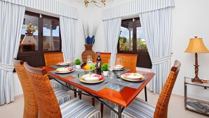 Ein Esszimmer mit einem Glastisch, Streifenstuhlen und einem Kronleuchter.