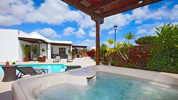 Ein Whirlpool mit Pool, Gartenmöbel und eine überdachte Terrasse.