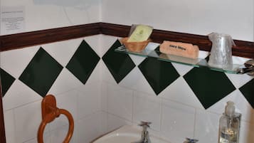 A bathroom with a sink, two faucets, a mirror, and a towel rack with folded towels.