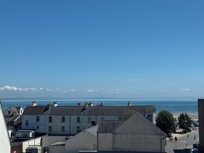 A coastal town with buildings, a clear sky, and the sea in the background.