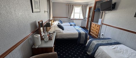 A hotel room with two beds, a desk with a chair, a television, and a window with curtains.