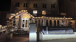Ein Hotel mit einem Schild, auf dem 'The Gower Hotel' steht, und einem Banner, das Sonntagsessen anwirbt.