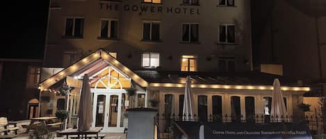 A hotel with a sign reading 'The Gower Hotel' and a banner advertising Sunday lunch.