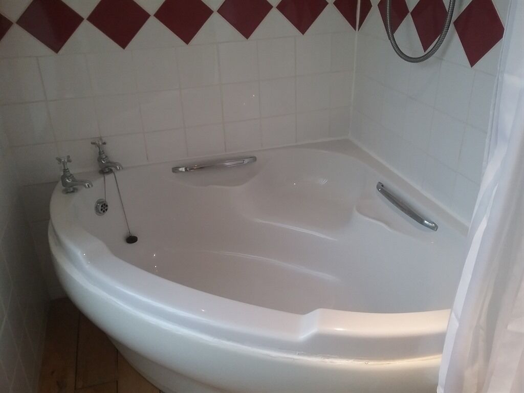 Una bañera con cabezal de ducha, desagüe y grifo.