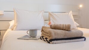 A neatly made bed with pillows, a folded towel, a cup, and a magazine. - Vacation Apartment 'Oasis Duna _ Casa Mate Pool' with Shared Pool, Private Terrace & Wi-Fi (Corralejo)