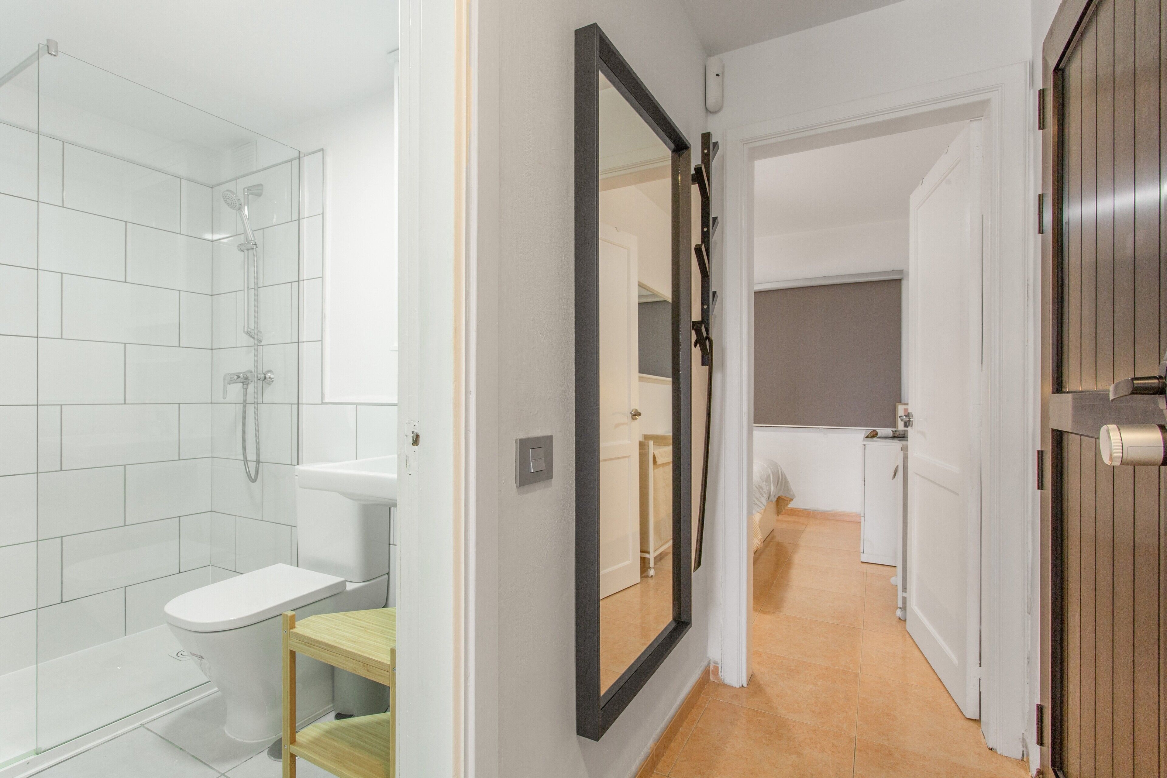 A modern bathroom with a shower, toilet, and a mirror.
