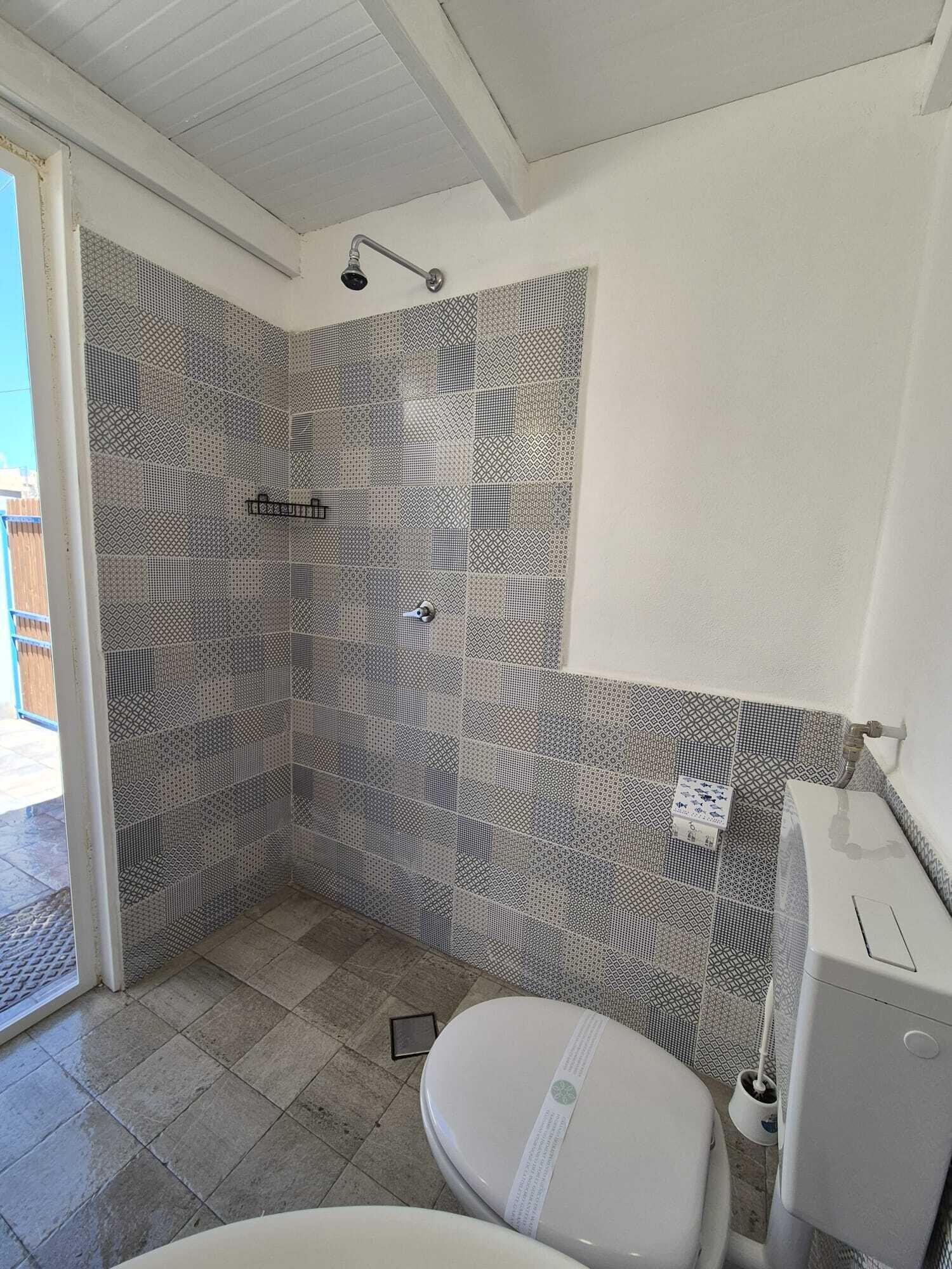 Une salle de bain avec des carreaux décorés, une douche, des toilettes et un bidet.